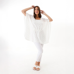 Poncho Magda de color blanco, con diseño ligero y suelto, modelado por una mujer que sonríe y posa con actitud.