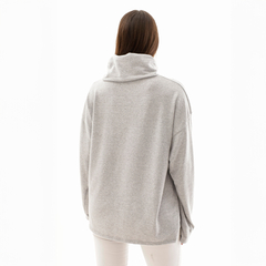 Vista trasera de un poncho polera gris con cuello alto, luciendo un diseño cómodo y moderno.