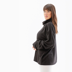 Poncho polera negra con cuello alto, vista lateral de una mujer posando.