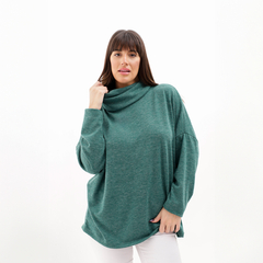 Poncho polera de color verde con un diseño holgado, modelo femenino posando con una mano en el rostro.