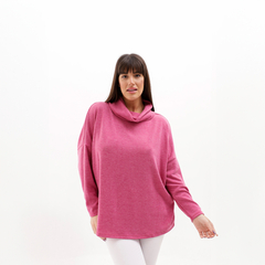 Poncho polera de color rosa, con cuello alto y mangas largas, modelado por una mujer