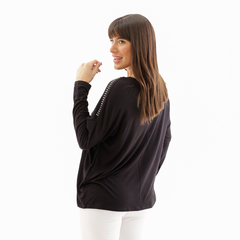 Remera Agys negra con detalles en los hombros, vista posterior de mujer con cabello largo y lacio.
