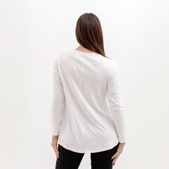 Vista trasera de una mujer usando una remera blanca de manga larga.