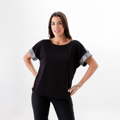 Remera Domi de color negro con mangas de diseño a rayas, modelada por una mujer posando.