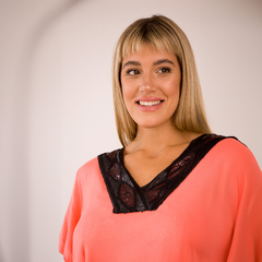 Modelo sonriente vistiendo una remera color coral con detalle negro en el escote.