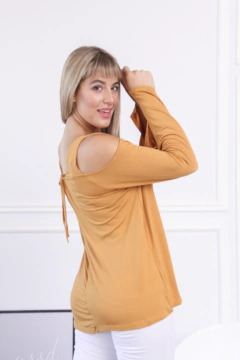 Remera Gladys de manga larga color mostaza con detalles en los hombros, modelo posando de espaldas.