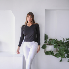 Remera Lena de manga larga negra, modelo posando en un ambiente moderno y minimalista con plantas.