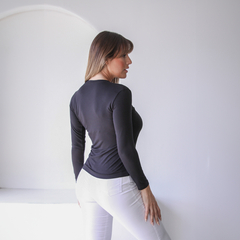 Remera Lena de manga larga en color negro, vista desde atrás, combinada con pantalones blancos.