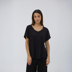 Remera Lindura negra con detalles en el escote, modelo femenino posando en un fondo blanco.