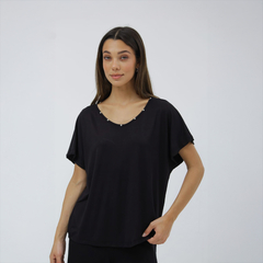 Remera negra de mujer con detalles en el escote y mangas amplias.