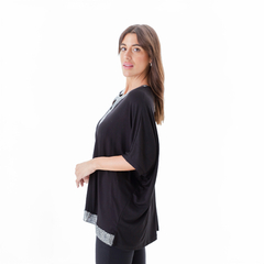 Remera Matilde de color negro con detalles en la parte inferior y un diseño holgado, vista lateral de una modelo.
