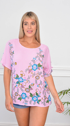 Remera Milán de manga corta en color rosa con estampado floral en tonos azules y verdes, llevada por una modelo.