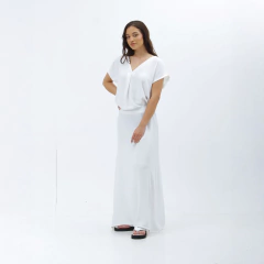 Modelo luciendo una remera larga blanca Nalami, de diseño sencillo y elegante, en un fondo blanco.
