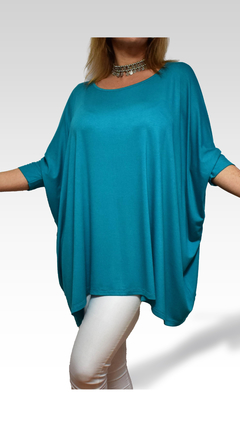Remerón Alma Largo en color azul turquesa, con mangas holgadas y diseño suelto, combinado con pantalones blancos.