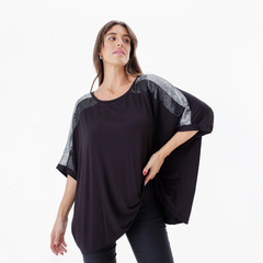 Modelo luciendo una blusa negra con detalles brillantes en las mangas, de la marca Remeron Amu.