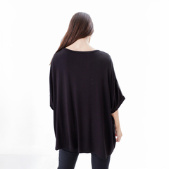 Mujer de espaldas vistiendo una blusa negra Remeron Amu, con un diseño amplio y cómodo.