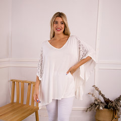 Modelo usando un remerón blanco con detalles en las mangas, posando en un entorno elegante.