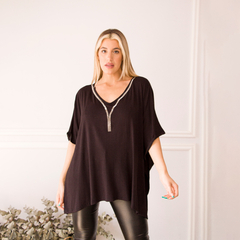 Remerón negro Chloe MC con detalle brillante en el escote, modelo femenino posando en un ambiente elegante.