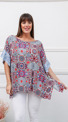 Remerón Coco con estampado colorido y detalles en encaje, modelado por una mujer que viste pantalones blancos.