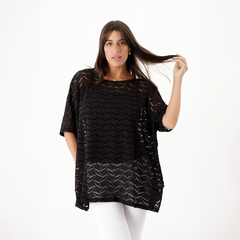 Remerón crochet negro con diseño de trama, modelo femenino que lleva pantalones blancos.