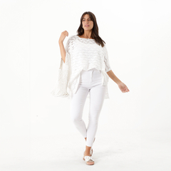 Modelo luciendo un remerón crochet blanco sobre un fondo blanco, con pantalones blancos y sandalias.