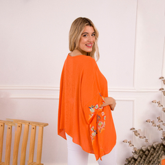 Remerón Flora de color naranja con bordados florales, mostrado por una modelo de perfil.
