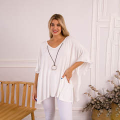 Remerón Indiana de color blanco, con un diseño amplio y cómodo, combinado con un collar negro, posando frente a una pared clara.