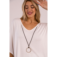 Mujer sonriente usando un remerón blanco con un collar de círculo en su cuello.