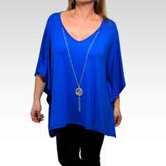 Remerón Indiana de color azul, con un diseño amplio y escote en V, acompañado de un collar largo con un colgante en espiral.