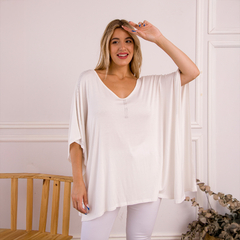 Remerón Indica blanco de manga corta, con un diseño elegante y detalles brillantes en el escote, luciendo alegre en un entorno minimalista.