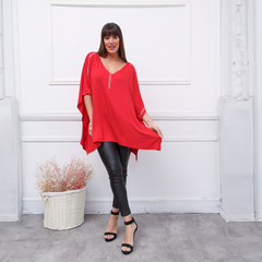 Modelo luciendo un remerón rojo de manga corta, combinado con pantalones de cuero y sandalias altas, en un entorno elegante.
