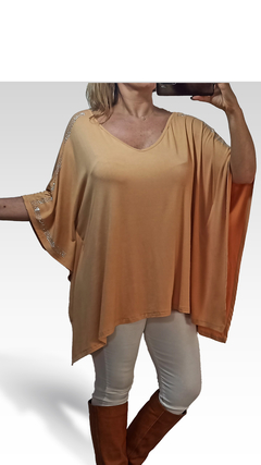 Remerón Indica de color melocotón con mangas amplias y detalles brillantes en los hombros, combinado con pantalones claros y botas marrones.