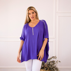 Remerón Indica de color púrpura, con detalles brillantes en los hombros, presentado por una modelo en un ambiente elegante.