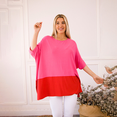 Remerón Jackie de color rosa y rojo, presentado por una mujer sonriente, en un entorno luminoso y decorativo.