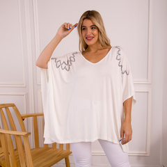 Remerón Janis blanco con detalles decorativos en las mangas, modelo posando en un entorno elegante.