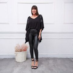 Modelo luciendo un reméron negro Janis con detalles brillantes, combinado con pantalones de cuero y sandalias, en un ambiente elegante.