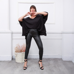 Modelo luciendo un reméron negro con detalles brillantes, combinado con pantalones de cuero negro y sandalias de taco alto.