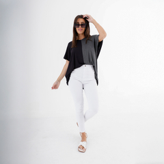 Modelo usando un remerón Juno en tonos gris y negro, combinado con pantalones blancos y sandalias.
