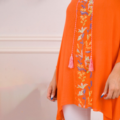 Remerón Maka color naranja con bordado floral y flecos en el centro.
