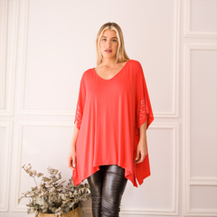 Remerón Sila en color rojo, con mangas amplias y detalles brillantes en las mangas, combinado con pantalones de cuero negros.