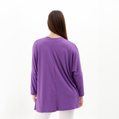 Vista trasera de una mujer usando una camiseta morada de manga larga.