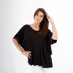 Modelo luciendo una blusa negra de la marca Remeron Verona, con detalles en las mangas y fondo blanco.