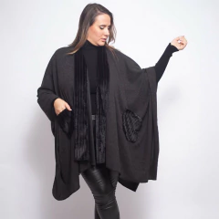 Modelo mujer vistiendo ruana negra Baeza con detalles en terciopelo y bolsillos, combinada con pantalones de cuero y suéter negro