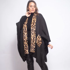 Modelo femenina usando ruana negra con detalles en animal print estilo leopardo en el borde frontal y bolsillo, combinada con pantalones de cuero negro y suéter de cuello alto negro