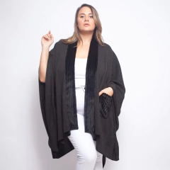Modelo mujer con ruana negra Baeza de diseño amplio con detalles en terciopelo y bolsillo frontal