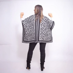 Vista trasera de mujer usando ruana Natal con diseño animal print en tonos blanco y negro