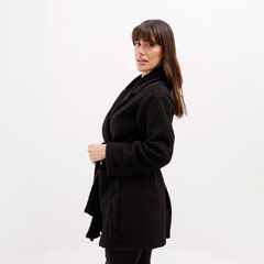 Mujer de perfil usando un abrigo negro de felpa, con cabello largo y lacio.
