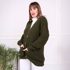 Saco inglés de color verde oscuro con botones, usado por una mujer en un ambiente luminoso.