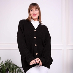 Saco inglés negro con botones en un ambiente luminoso, modelo sonriente con blusa blanca.