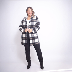 Mujer sonriente vistiendo un saco Rusia de cuadros en blanco, negro y gris, combinado con pantalones y botas negras
